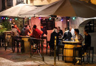 People drink in a bar terrace before the start of a new coronavirus curfew, in Bayonne, southwestern France, Thursday, Oct. 22, 2020. Curfews loom for Italy’s three largest cities face new curfews, and similar overnight off-the street rules were decided on Thursday for elsewhere in Europe, including Athens and much of France. (AP Photo/Bob Edme)