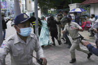 Cambodian-American lawyer Theary Seng, rear center, dressed in the Lady Liberty, is escorted by local police officers outside Phnom Penh Municipal Court in Phnom Penh, Cambodia, Tuesday, June 14, 2022. The Cambodian American lawyer and dozens of members of a now-dissolved opposition party were convicted of treason Tuesday in a trial that was the latest move to tame all opposition to the long-running rule of Prime Minister Hun Sen. (AP Photo/Heng Sinith)