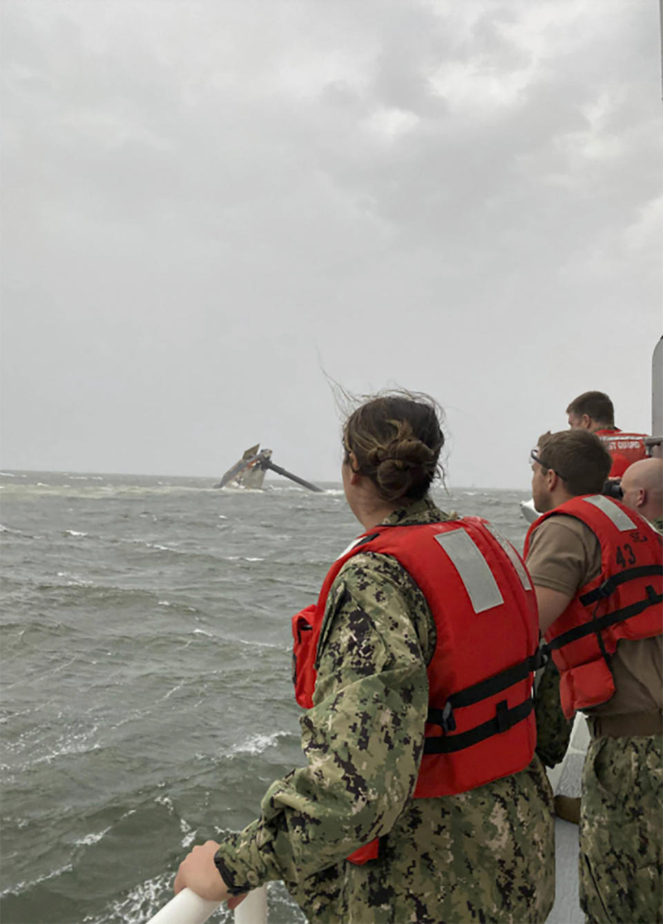 In this photo provided by the U.S. Coast Guard, crew members of the Coast Guard Cutter Glenn Harris scan the water while searching for those missing Tuesday, April 13, 2021, after a 175-foot commercial lift boat capsized 8 miles south of Grand Isle, La. The Seacor Power, an oil industry vessel, flipped over Tuesday in a microburst of dangerous wind and high seas. (U.S. Coast Guard via AP)