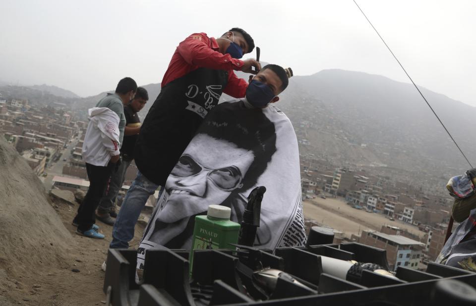 Barber Josue Yacahuanca styles the hair of a resident free of charge at the top of a hill in the San Juan de Lurigancho neighborhood of Lima, Peru, Friday, June 19, 2020. "I want them to look in the mirror and see a bit of hope," said Yacahuanca, who's just 21 years old but already considers himself a veteran barber because he starting cutting hair age 13. (AP Photo/Martin Mejia)