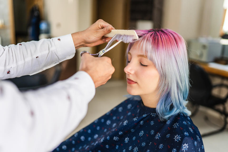 Young woman with coloured hair getting a haircut at the hairdresser