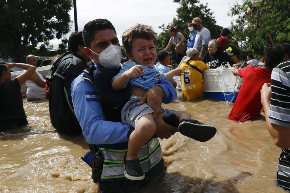 A toddler is carried over a flooded street in the aftermath of Hurricane Eta in Jerusalen, Honduras, Thursday, Nov. 5, 2020. The storm that hit Nicaragua as a Category 4 hurricane on Tuesday had become more of a vast tropical rainstorm, but it was advancing so slowly and dumping so much rain that much of Central America remained on high alert. (AP Photo/Delmer Martinez)