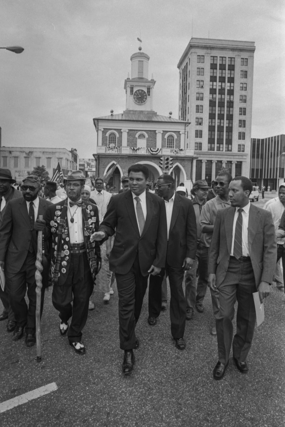 Muhammad Ali, center, in procession from Market House with local Muslims on May 4, 1991. The man in the front on the far right is Adam Beyah, who at the time was the imam of Masjid Omar Ibn Sayyid. The man to Ali's right with the walking stick is Mitch Capel, a.k.a. "Granddaddy June Bug."