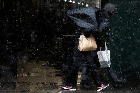 A woman struggles with her umbrella in the wind and snow in New York City, U.S. March 10, 2017. REUTERS/Brendan McDermid