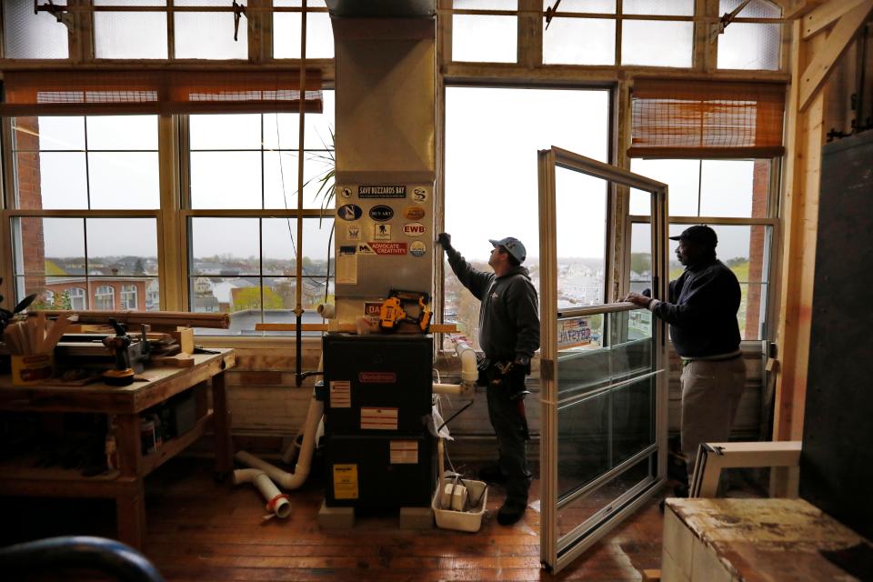 Crews install new windows in the upper levels of the Hatch Street Studios in New Bedford.