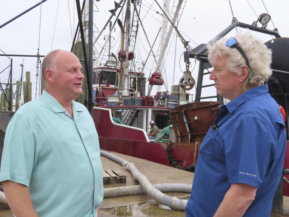 Brick Wenzel, left, a commercial fisherman, and Jim Hutchinson, managing editor of The Fisherman magazine, talk on a seafood dock in Point Pleasant Beach, N.J., on June 20, 2023. The commercial and recreational fishing industry has numerous concerns over offshore wind projects. The wind industry says it has tried to address those concerns, and will pay compensation for those that can't be avoided. (AP Photo/Wayne Parry)