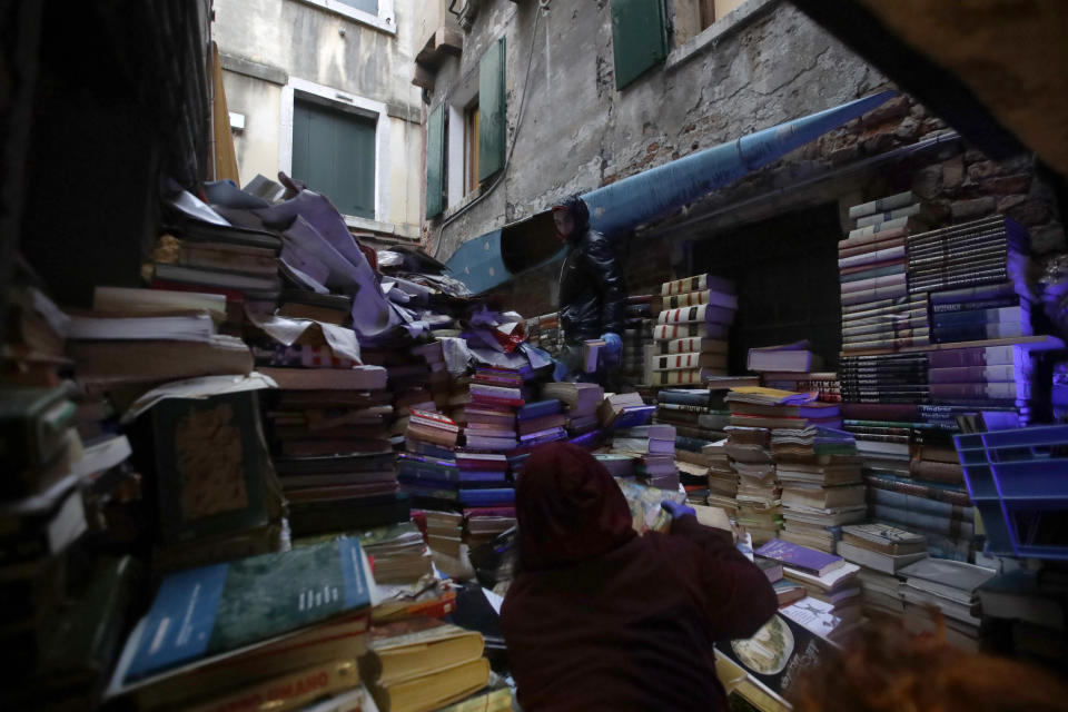 Volunteers pile up damaged books from renowned bookstore "Acqua Alta" (High Water) after flooding in Venice, Italy, Friday, Nov. 15, 2019. Exceptionally high tidal waters returned to Venice on Friday, prompting the mayor to close the iconic St. Mark's Square and call for donations to repair the Italian lagoon city just three days after it experienced its worst flooding in 50 years. (AP Photo/Luca Bruno)