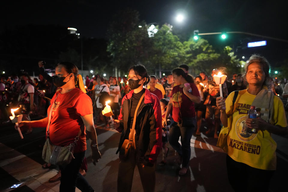 Devotees, some wearing face masks, hold candles as they join the "Walk of Faith" procession as part of celebrations for the feast day of the Black Nazarene, a centuries-old charred statue of Jesus Christ, on Sunday, Jan. 8, 2023, in Manila, Philippines. The annual Black Nazarene feast day which will be held on Jan. 9 draws massive numbers of devotees who pray for the sick and a better life in this predominantly Roman Catholic nation. (AP Photo/Aaron Favila)