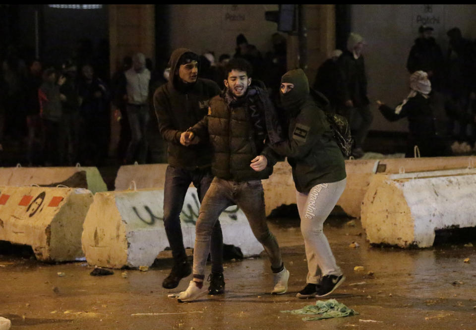 Anti-government protesters help their friend who injured while clashing with the riot police, during ongoing protests against the political elites who have ruled the country since decades, in Beirut, Lebanon, Sunday, Jan. 19, 2020. (AP Photo/Hassan Ammar)