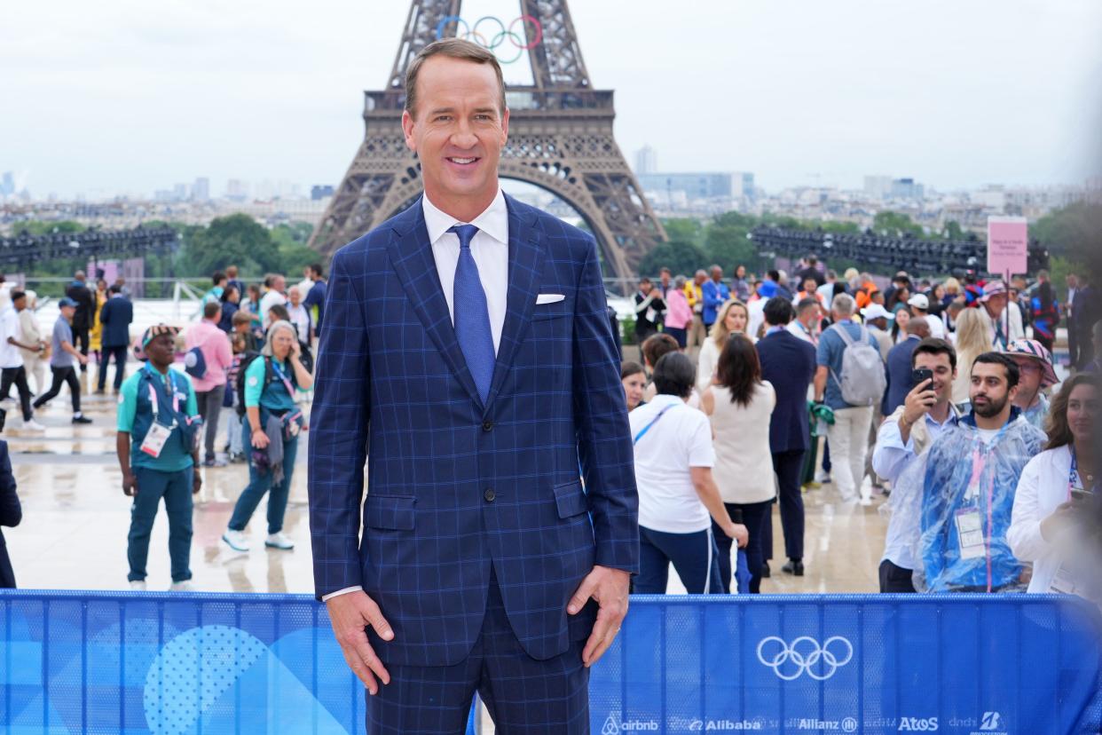 Peyton Manning poses for a photo in front of the Eiffel Tower.