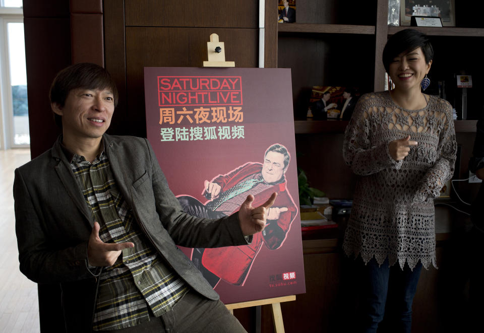 Sohu Chairman and CEO Charles Zhang, left, strikes a pose next to a poster of American irreverent comedy sketch show Saturday Night Live, after a press conference at the Sohu Media Plaza in Beijing Thursday, Jan. 2, 2014. The late-night U.S. comedy sketch show that regularly mocks politicians, popular culture and celebrities is being shown exclusively on the website of Sohu Video, a unit of Chinese online media group and Nasdaq-listed Sohu.com Inc. (AP Photo/Andy Wong)