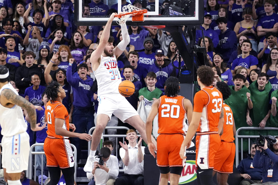 Northwestern center Matthew Nicholson (34) hangs from the rim after dunking against Illinois during the first half of an NCAA college basketball game in Evanston, Ill., Wednesday, Jan. 24, 2024. (AP Photo/Nam Y. Huh)