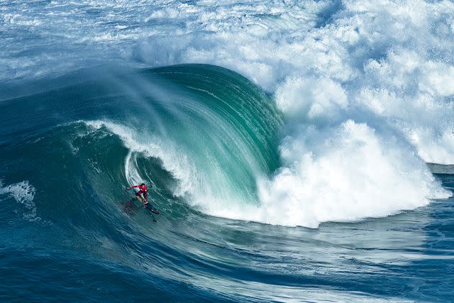 <p>Hugo Amaral/SOPA Images/LightRocket/Getty</p> Kai Lenny rides a wave during the Nazare Challenge in Portugal in November 2018.