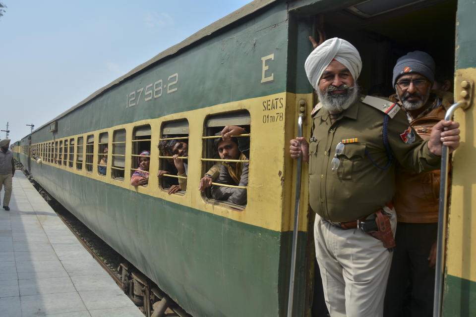 An Indian policeman and passengers from Pakistan look on from the Samjhauta Express train as it arrives in Atari, India, Monday, March 4, 2019. A Pakistani railway official said the key train service with neighboring India has resumed in another sign of easing tensions between the two nuclear-armed rivals since a major escalation last week over disputed Kashmir region. (AP Photo/Prabhjot Gill)