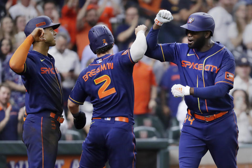 Houston Astros', from left, Jeremy Pena, Alex Bregman and Yordan Alvarez celebrate after they all scored on the three run home run by Alvarez, tying the game against the Detroit Tigers during the fifth inning of a baseball game Monday, April 3, 2023, in Houston. It was Alvarez's 100th career home run. (AP Photo/Michael Wyke)