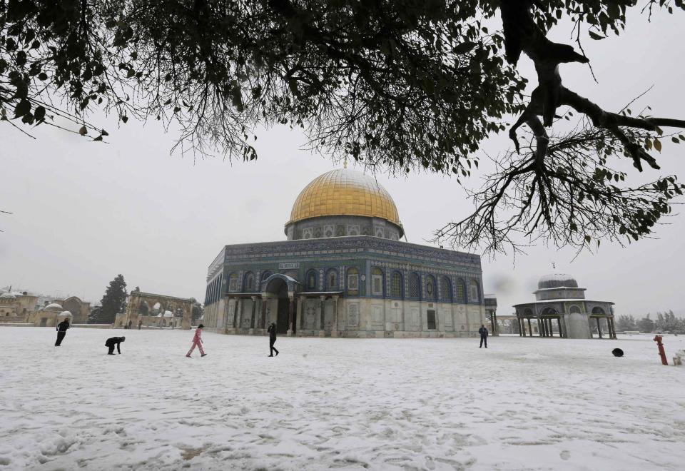 People walk in front of the snow capped Dome of the Rock in Jerusalem's Old City