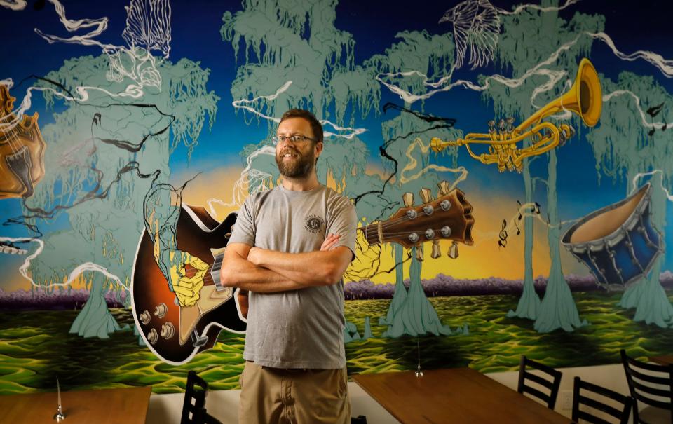 Jeremy Baker stands in front of a mural painted by longtime friend Hunter Bougis Baker at Grace Note Brewing, a new craft brewery at 4591 Lakeside Drive Suite 108 at Winward Sadler Point Marina in Jacksonville.