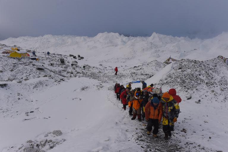 An injured person is carried by rescue members to be airlifted by rescue helicopter at Everest Base Camp on April 26, 2015, a day after an avalanche triggered by an earthquake devastated the camp