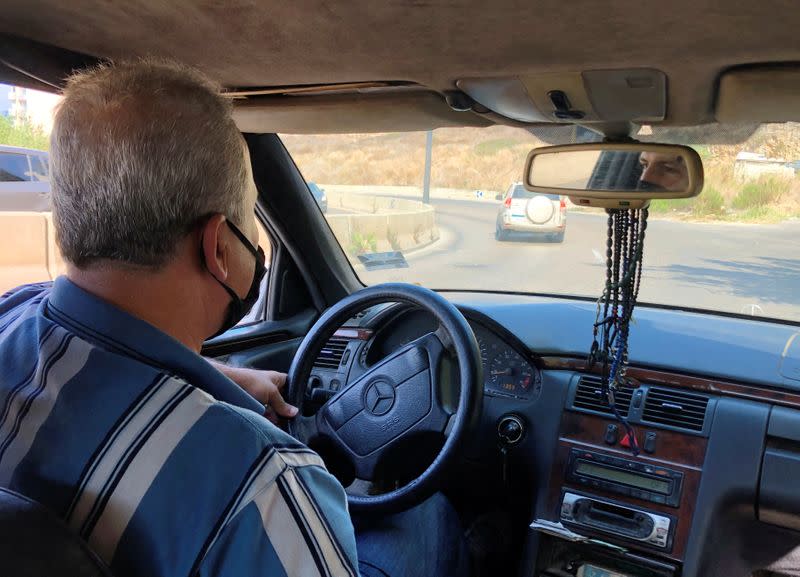 Fouad Khamasi wears a protective mask as he drives his cab in Beirut