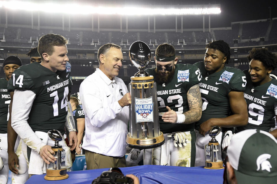 Michigan State head coach Mark Dantonio, center-left, holds up the Holiday Bowl trophy after beating Washington State 42-17. (AP Photo/Denis Poroy)