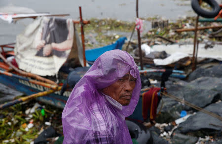 A fisherman stays next to his boat docked along the shore in Manila bay after Typhoon Sarika slammed central and northern Philippines, October 16, 2016. REUTERS/Erik De Castro