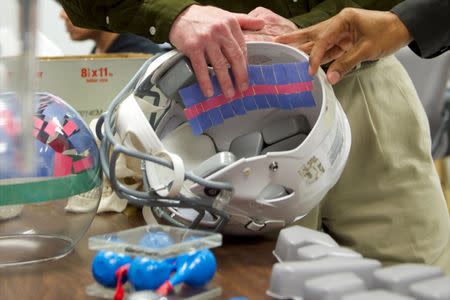 Ghatu Subhash (R) and his research partner Keith Peters (L) show how their fluid-filled pouches will fit inside football helmets to prevent concussions in their lab at the University of Florida in Gainesville, Florida, in this January 13, 2014, file photo. REUTERS/Steve Johnson/Files