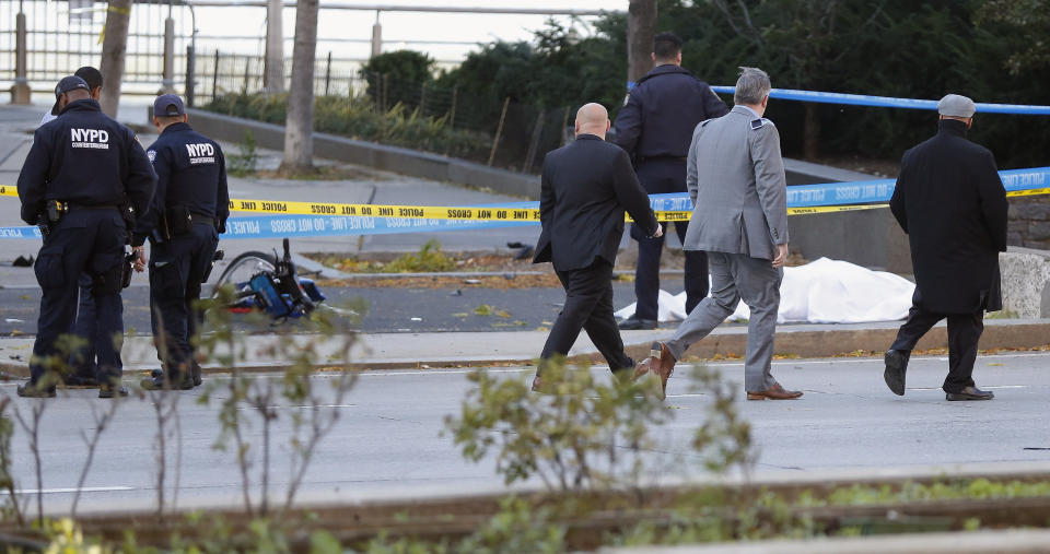 <p>New York Police Department officers investigate the scene around a body covered under a white sheet next to a mangled bike along the bike path, Oct. 31, 2017, in New York. (Photo: Bebeto Matthews/AP) </p>