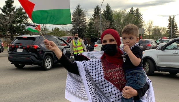 A woman waves a Palestinian flag during a car convoy organized by pro-Palestinian demonstrators in Edmonton on Saturday.