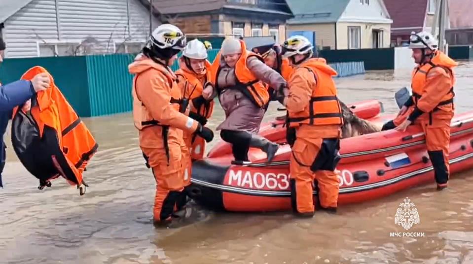 In this grab taken from a video released by the Russian Emergency Ministry Press Service on Saturday, April 6, 2024, emergency workers evacuate a local resident after a part of a dam burst causing flooding, in Orsk, Russia. Floods hit a city in the Ural Mountains areas after a river dam burst there, prompting evacuations of hundreds of people, local authorities said. The dam breach in Orsk, a city less than 20 kilometers north of Russia’s border with Kazakhstan, occurred on Friday night, according to Orsk mayor Vasily Kozupitsa. (Russian Emergency Ministry Press Service via AP)