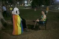 A man dressed in a panda costume sits covered by the gay pride flag during a protest against the violence towards the gay community in Tel Aviv August 1, 2015. REUTERS/Baz Ratner