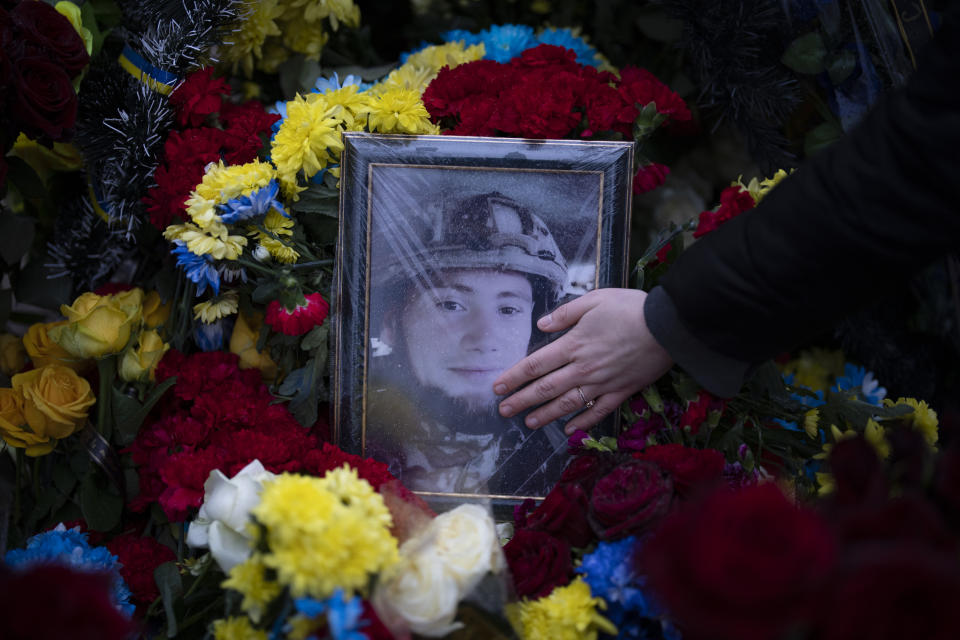 Anna Korostenska touches a picture of her late fiancee, Oleksii Zavadskyi, at his grave in Bucha, Ukraine, Monday, Jan. 23, 2023. As the conflict that killed her loved one still rages on, Anna wrestles with a question that all of war-torn Ukraine must grapple with: After loss, what comes next? (AP Photo/Daniel Cole)