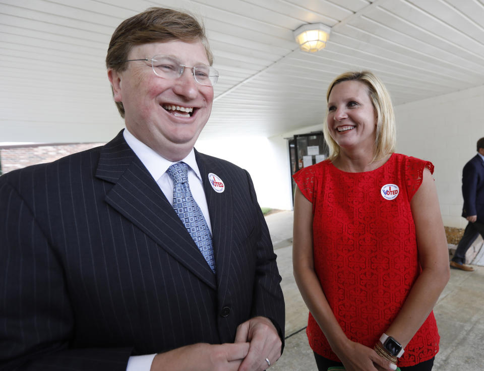 Lt. Gov. Tate Reeves, left, and his wife Elee Reeves, share a laugh as he speaks with reporters about the final days of the runoff campaign, for the GOP nomination for governor, Tuesday, Aug. 27, 2019 at his Flowood, Miss., voting precinct. Reeves faces former Mississippi Supreme Court Chief Justice Bill Waller Jr., for the party's nomination. (AP Photo/Rogelio V. Solis)