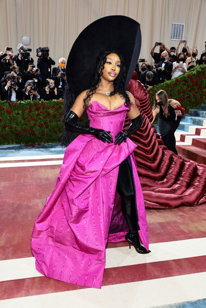 SZA in a huge hat and a gown with long boots