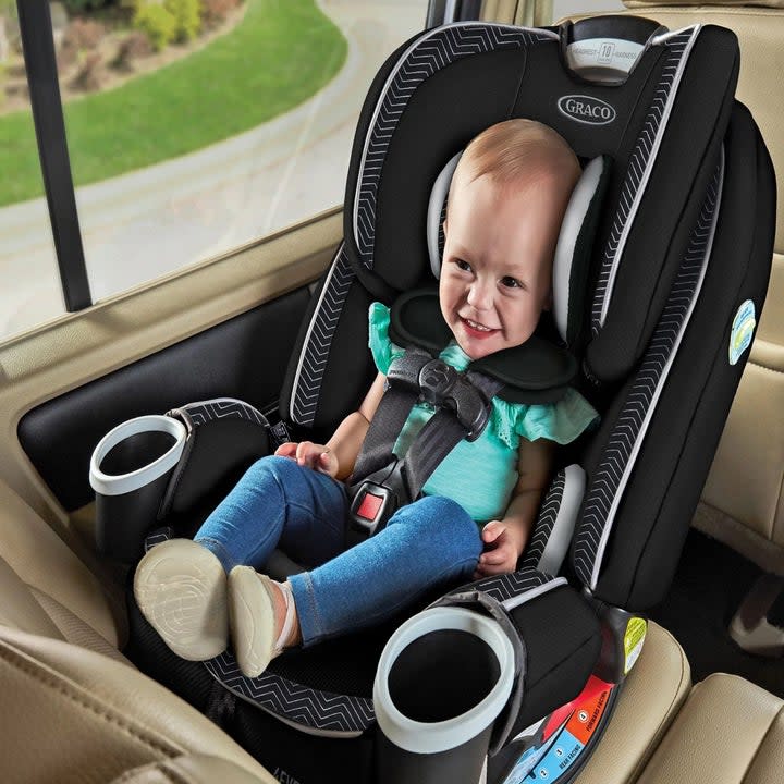 An infant sitting in the car seat in the rear-facing harness mode