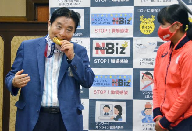 Nagoya city Mayor Takashi Kawamura bites the Olympic gold medal of softball pitcher Miu Goto during a ceremony in Nagoya on Aug. 4. (Photo: KYODO Kyodo via Reuters)