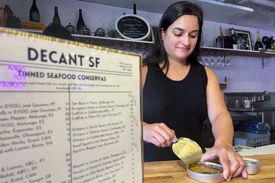 DECANTsf co-founder Simi Grewal opens up tinned fish inside the bar, Friday, Oct. 13, 2023, in San Francisco. (AP Photo/Haven Daley)