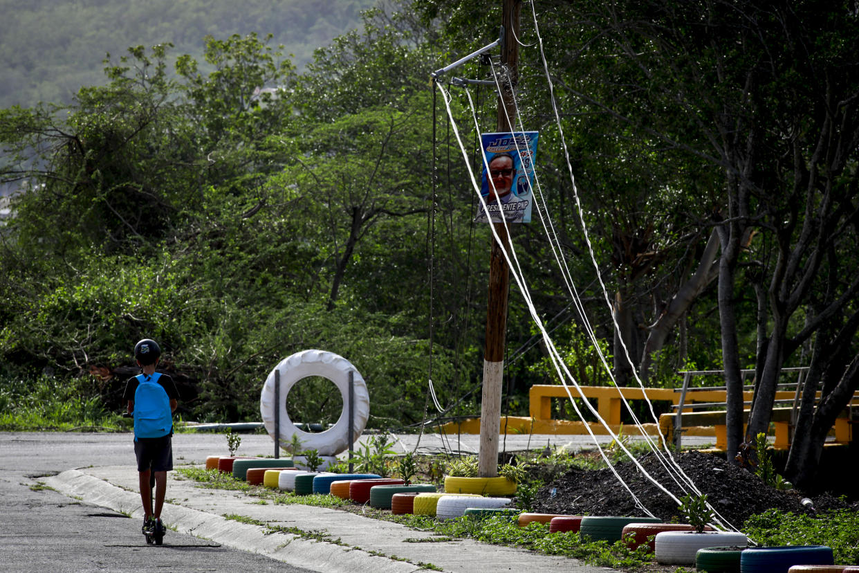 A kid rides a scooter past downed electricity lines on Sept. 20, 2022, in Salinas, Puerto Rico. (Jose Jimenez / Getty Images)