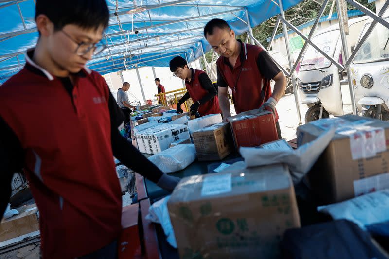 Delivery workers sort packages on a conveyor belt, ahead of the "618" shopping festival, at a logistics station in Beijing