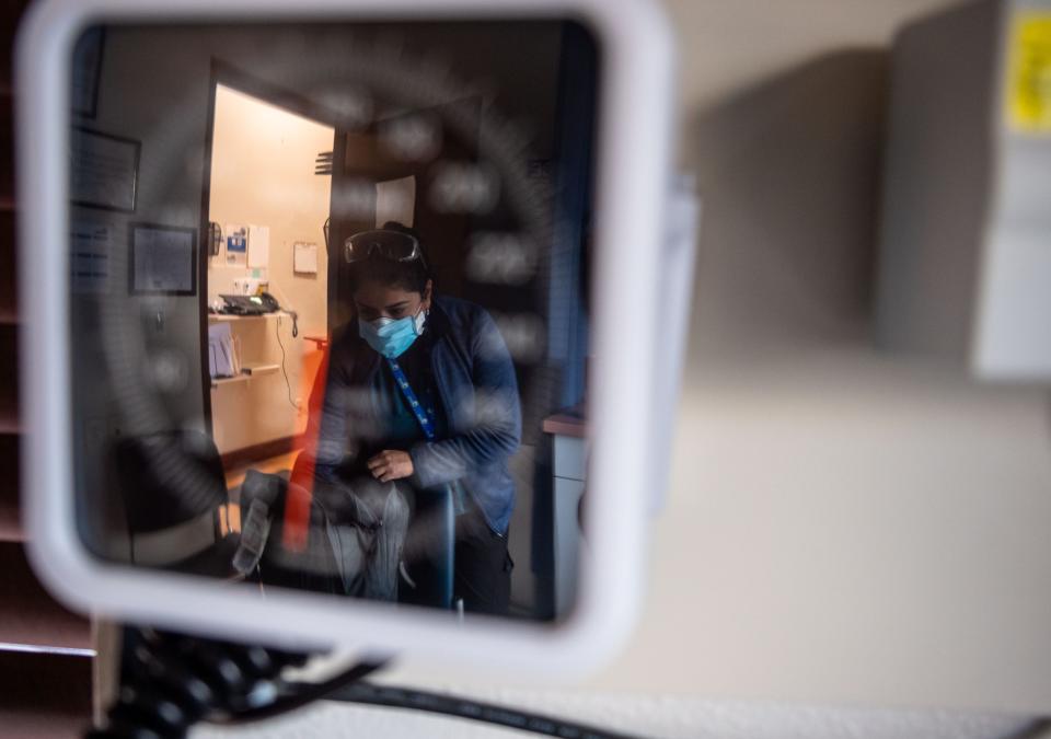 Dr. Olga Magdalena Padron Lopez is reflected in a blood pressure scale as she looks through her backpack inside the COVID-19 test room at the Clinica de Salud Del Valle de Salinas in Greenfield, Calif., on Dec. 8, 2021.