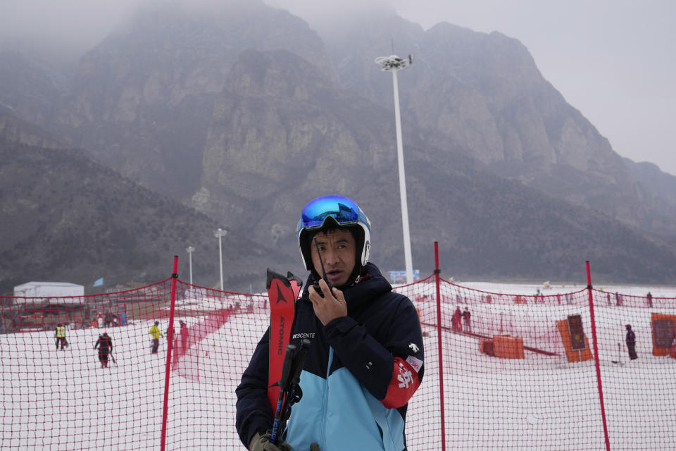 Farmer-turned-ski coach Li Wei speaks into this walkie-talkie at the Vanke Shijinglong Ski Resort in Yanqing on the outskirts of Beijing, China, Thursday, Dec. 23, 2021. The Beijing Winter Olympics is tapping into and encouraging growing interest among Chinese in skiing, skating, hockey and other previously unfamiliar winter sports. It's also creating new business opportunities. (AP Photo/Ng Han Guan)