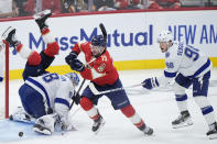 Florida Panthers defenseman Brandon Montour flips over Tampa Bay Lightning goaltender Andrei Vasilevskiy (88) as left wing Matthew Tkachuk (19) chases the puck followed by defenseman Mikhail Sergachev (98) during the first period of Game 5 of the first-round of an NHL Stanley Cup Playoff series, Monday, April 29, 2024, in Sunrise, Fla. (AP Photo/Wilfredo Lee)