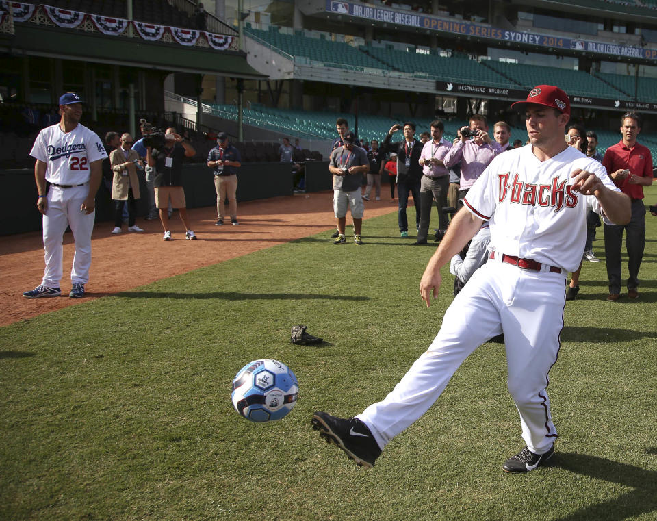 The Los Angeles Dodgers' Clayton Kershaw, left, watches as the Arizona Diamondbacks' Paul Goldschmidt, right, kicks a soccer ball at the Sydney Cricket Ground in Sydney, Wednesday, March 19, 2014. The MLB season-opening two-game series between the Dodgers and Diamondbacks in Sydney will be played this weekend. (AP Photo/Rick Rycroft)