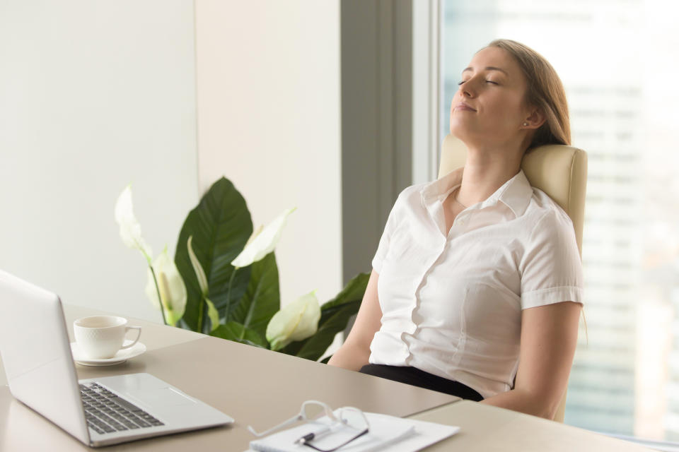 Pictured: female officeworker closes her eyes at her desk. Image: Getty