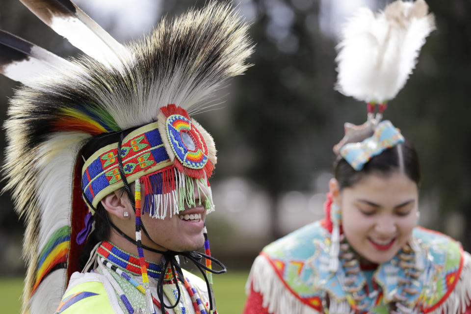 In this photo taken Saturday, April 4, 2020, Wakiyan Cuny, left, and his sister Wicahpi Cuny, 14, Dakota and Lakota tribal members, smile as they are interviewed during a live streamed powwow after dancing in a park near their home in Puyallup, Wash. The largest powwows in the country have been canceled or postponed amid the spread of the coronavirus. Tribal members have found a new outlet online with the Social Distance Powwow. They're sharing videos of colorful displays of culture and tradition that are at their essence meant to uplift people during difficult times. (AP Photo/Elaine Thompson)