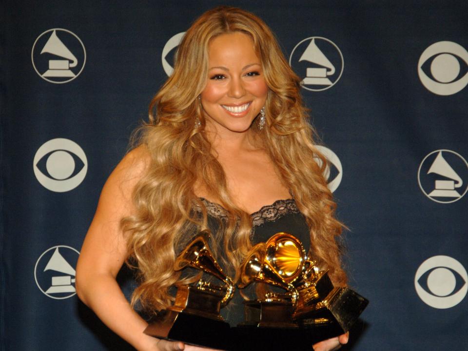 Mariah Carey holding her multiple grammys in 2006