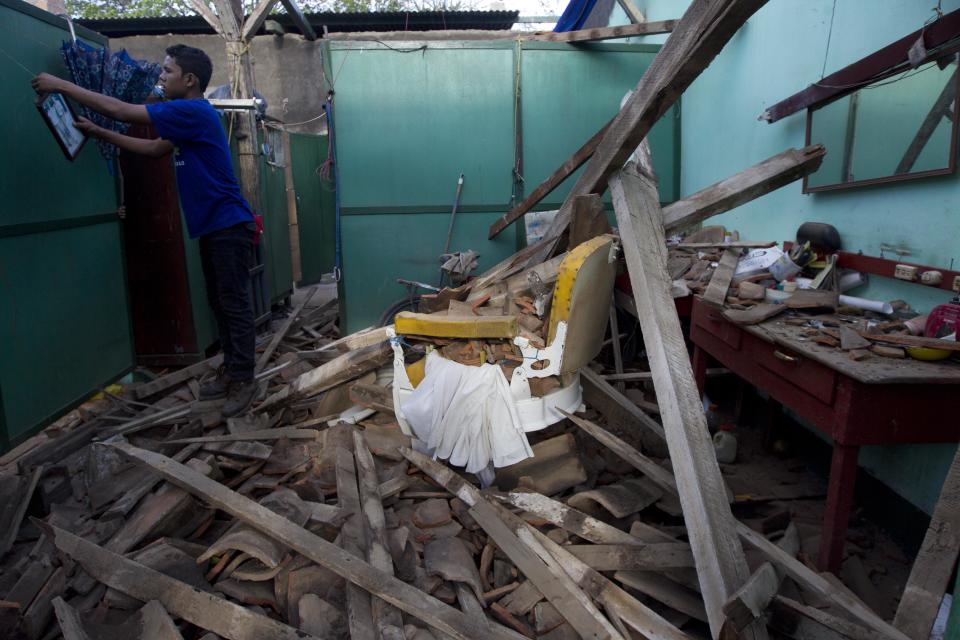 Un hombre retira un cuadro desde el muro de una peluquería destruida por el fuerte sismo que azotó la localidad de Nagarote, en el oeste de Nicaragua, el jueves 10 de abril de 2014. El temblor de magnitud 6,1 dañó decenas de viviendas y dejó un muerto y más de 200 heridos. El presidente Daniel Ortega decretó el alerta roja en todo el país tras las continuas réplicas que siguieron al sismo. (AP Foto/Esteban Félix)