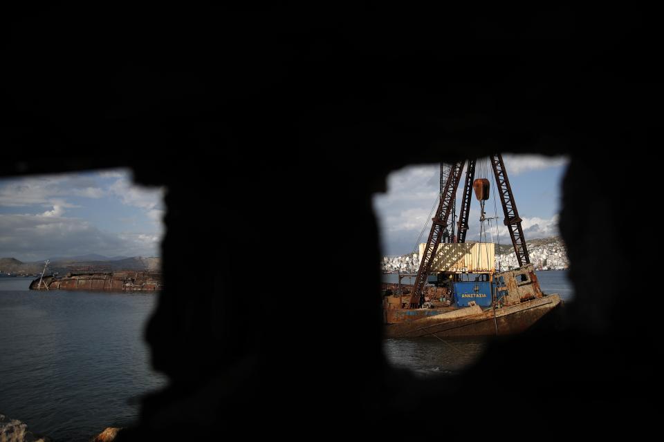 A floating crane holds an old vessel in Damari, an area with eleven shipwrecks, during shipwreck raising operation on Salamina island, west of Athens, on Friday, Nov. 8, 2019. Greece this year is commemorating one of the greatest naval battles in ancient history at Salamis, where the invading Persian navy suffered a heavy defeat 2,500 years ago. But before the celebrations can start in earnest, authorities and private donors are leaning into a massive decluttering operation. They are clearing the coastline of dozens of sunken and partially sunken cargo ships, sailboats and other abandoned vessels. (AP Photo/Thanassis Stavrakis)