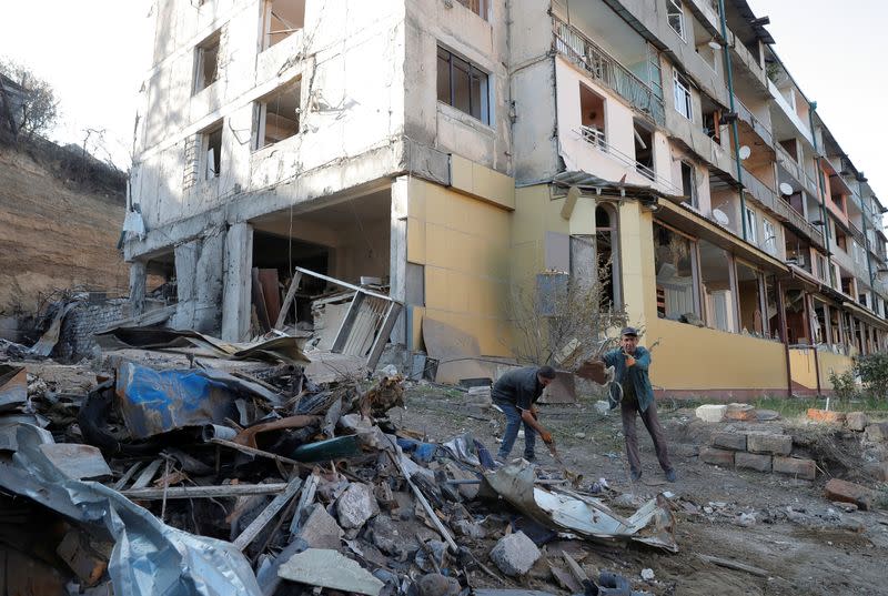 Workers remove debris near a residential building, which was damaged during the military conflict over the breakaway region of Nagorno-Karabakh, in Stepanakert