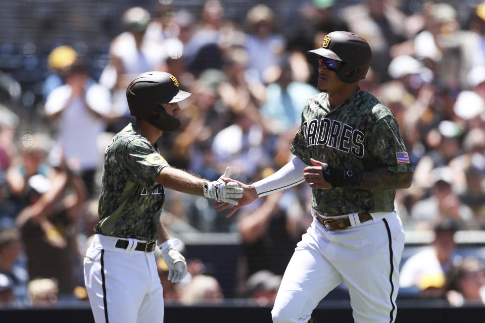 San Diego Padres' Manny Machado, right, celebrates with Adam Frazier after scoring on a double by Jake Cronenworth against the Colorado Rockies, in the first inning of a baseball game Sunday, Aug. 1, 2021, in San Diego. (AP Photo/Derrick Tuskan)