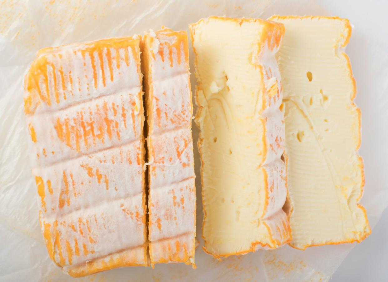 Cheeseboard with Sliced Yellow Limburger Cheese Top View. Herve or Reblochon cheeses on Paper Background